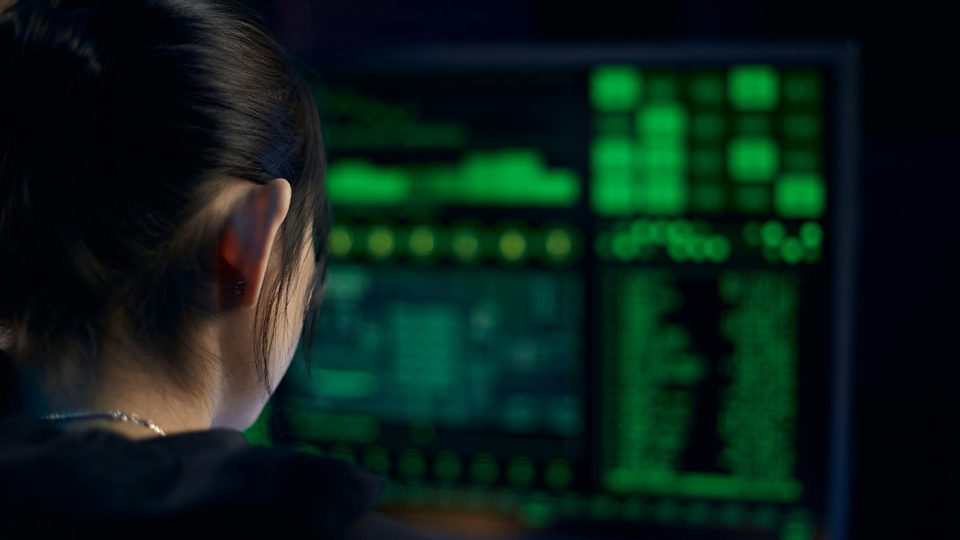 A woman standing in front of a large illuminated computer display.