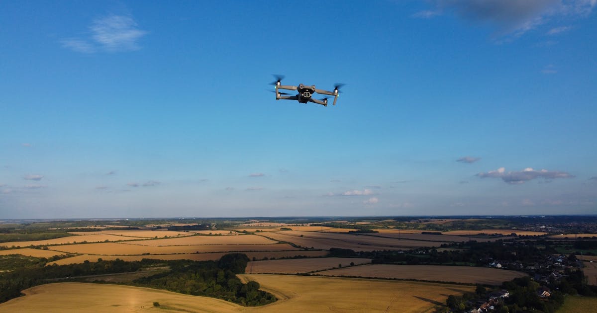 Drone flying over farmland under a blue sky