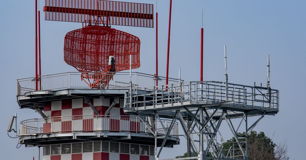 Red and white radar tower against a blue sky