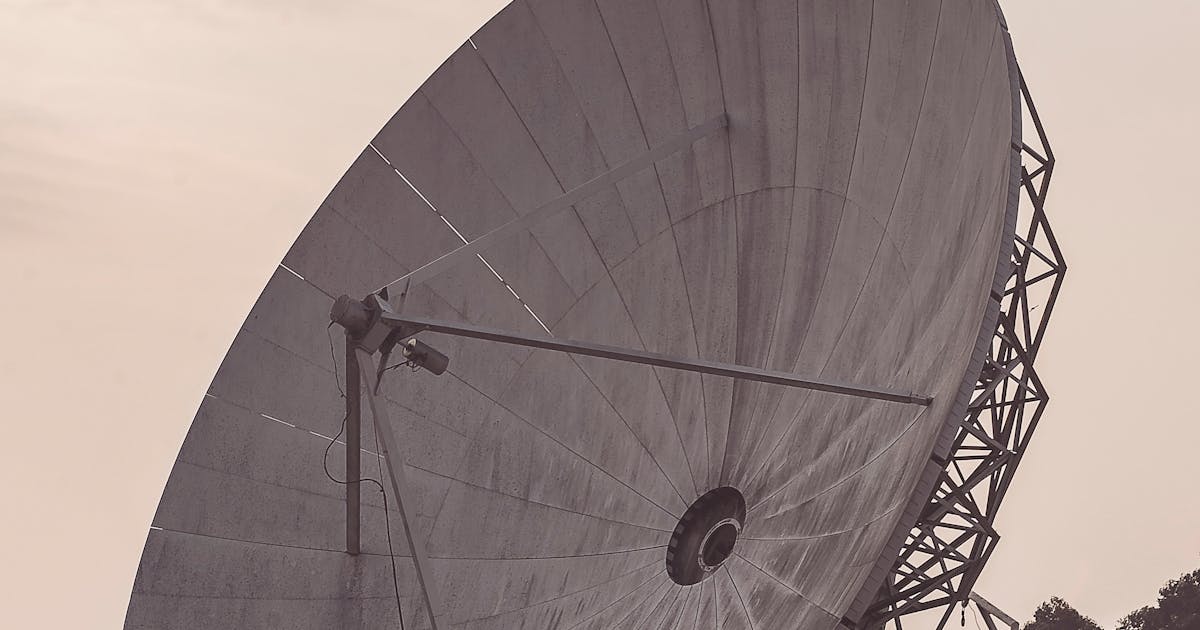 Parabolic communication antenna against a cloudy sky